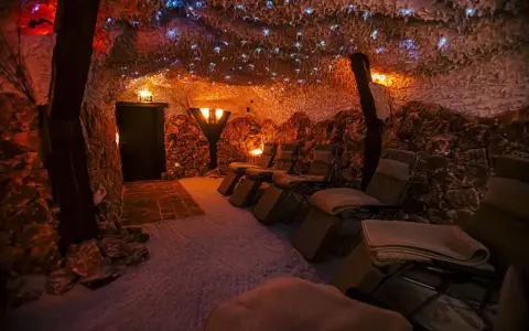 Entspannende Liegestühle in einer **Salzgrotte Paderborn**. Die Wände sind mit Salzsteinen verkleidet, die Decke funkelt mit kleinen Lichtern.