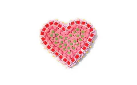 Corazón de tartas de chuches de San Valentín, decorado con flores rosas y detalles verdes.