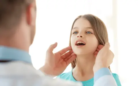 Medico controlla i linfonodi del collo di una bambina.