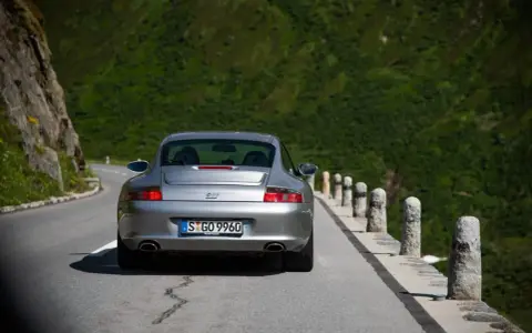 Silberner Porsche 996 4S auf Bergstraße. Ein Klassiker mit Potenzial für Wertsteigerung, der die Freiheit der Fahrt genießt.