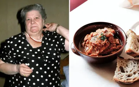 Una donna con un vestito a pois guarda verso la telecamera, accanto a una ciotola di trippa alla romana con pane.