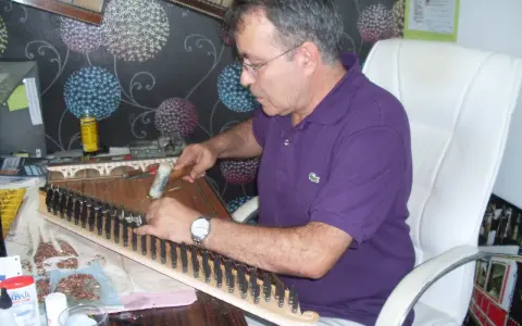 Un artisan ajuste les cordes d'un kanun, instrument de musique traditionnel, avec un marteau.