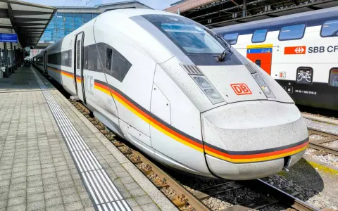 ICE train with German flag colors at a station, ready for a journey between Germany and Switzerland.