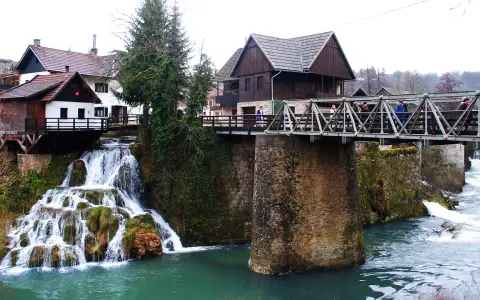 Rastoke, Croazia: cascate e mulini sull'acqua. Un ponte metallico attraversa il fiume, collegando case tradizionali.