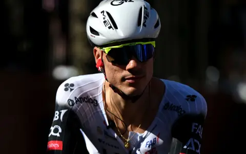 Juan Ayuso, Radsportler im weißen Trikot mit schwarzen Akzenten, trägt einen weißen Helm und eine gelbe Sportbrille.