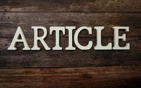 Białe litery układają się w słowo "ARTICLE" na drewnianym tle. To zapowiedź rozszerzonego artykułu po angielsku.