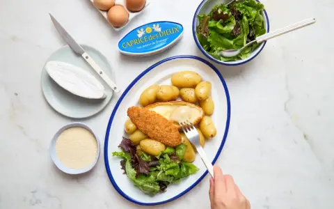 Délicieuse recette Caprice des Dieux pané, servi avec des pommes de terre et une salade verte. Le fromage coulant est irrésistible !