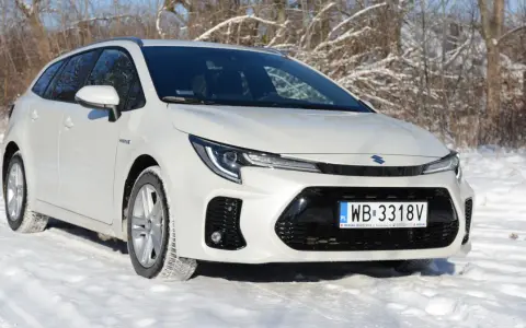 Biały Suzuki Swace Hybrid na śniegu, gotowy na zimowe wyzwania.