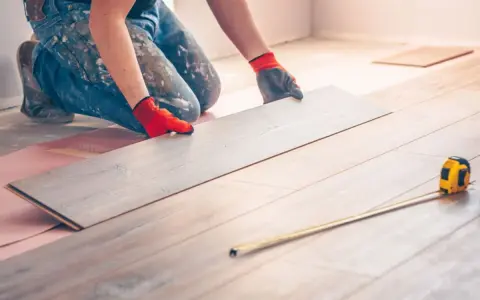 Handwerker verlegt Laminat. Eine Dehnungsfuge ist wichtig, damit sich das Holz ausdehnen kann.