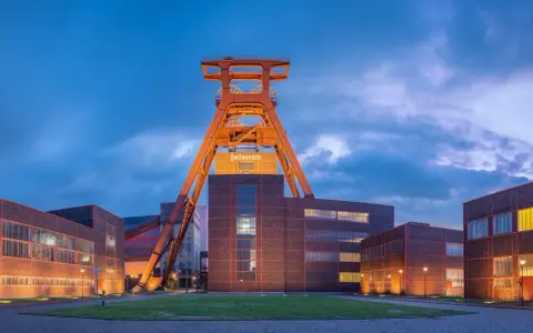 Industrielles Erbe: Der Förderturm des Zollverein 1834 ragt über die beleuchteten Backsteingebäude.