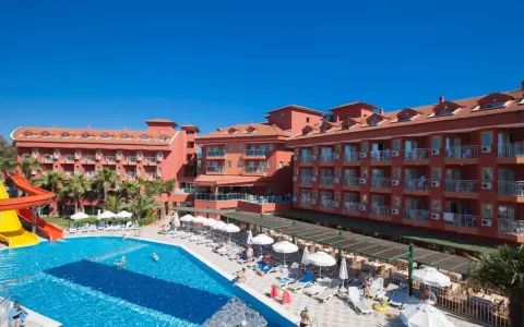 Słoneczny dzień w club side coast. Basen z wodnymi zjeżdżalniami, leżaki i palmy przy hotelu.
