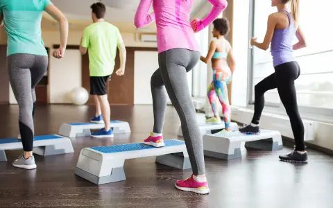 Persone in palestra eseguono attività aerobica a bassa intensità esempi: step-up.