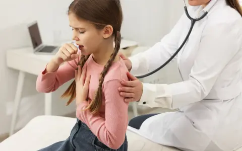 Bambina con trecce tossisce, appoggiando una mano sul petto. Un medico con camice bianco la ascolta con lo stetoscopio, preoccupato per i continui colpetti di tosse bambini.