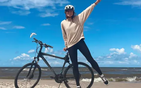 Dziewczyna w kasku na rowerze na plaży. Wspaniała infrastruktura rowerowa nad morzem.