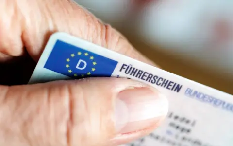 Nahaufnahme eines Führerscheins, der von einer Hand gehalten wird. Die Person könnte versucht sein, trotz Fahrverbot zu fahren.