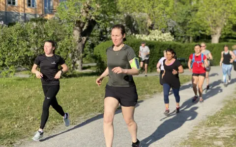 En grupp löpare på en grusväg, en del med fokus på att få upp konditionen snabbt. Solen skiner och träden är gröna.