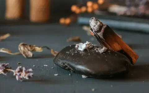 Dym z drewna palo santo unosi się nad gładkim, czarnym kamieniem, sugerując rytuał, jak ładować kamienie energią.