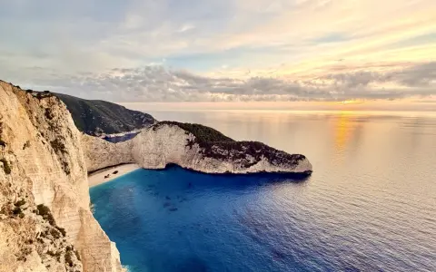 Zachód słońca nad Navagio, słynną zatoką wraku na Zakynthos. Białe klify, turkusowa woda i wrak statku tworzą malowniczy krajobraz.