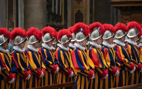 Guardie svizzere in divisa colorata, con elmi piumati, spiegano perchè il Papa ha le guardie svizzere: sono la sua protezione storica.