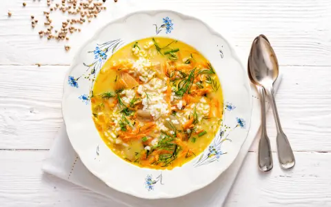 Aromaticzna zupa koperkowa z ryżem, marchewką i kawałkami kurczaka, udekorowana świeżym koperkiem.