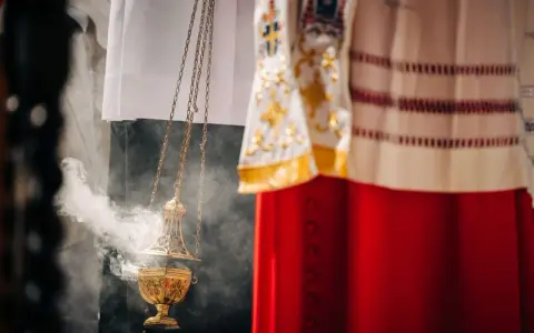 Złota kadzielnica unosi dym podczas uroczystości. W tle widać szaty liturgiczne, przypominające o święta nakazane.