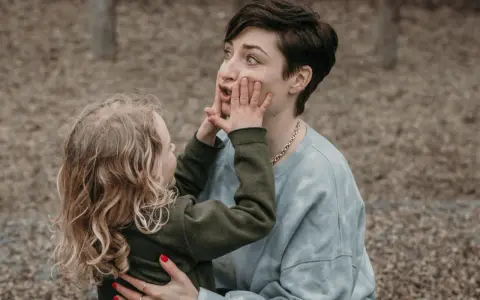 Kind drückt der beleidigten Mutter die Wangen zusammen.