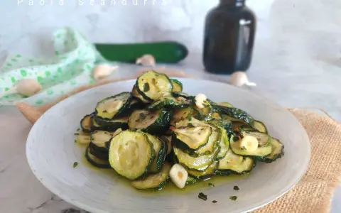 Piatto di zucchine alla scapece, fette sottili condite con olio, aglio e prezzemolo.