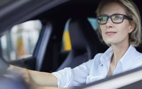 Frau mit Brille fährt Auto. Ohne Brille fahren ohne Brille Strafe.