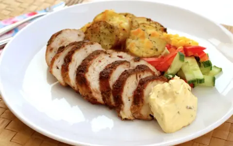 Skivad kycklingfilé i ugn, perfekt tillagad med krispiga potatisskivor, färsk sallad och en klick krämig sås.