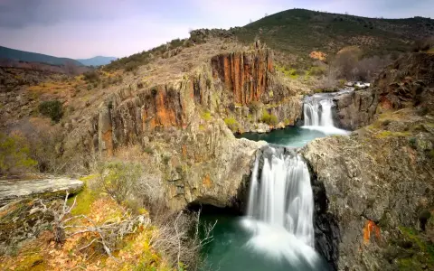 Cascadas en el río Guadalajara, rodeadas de rocas rojizas y vegetación otoñal.