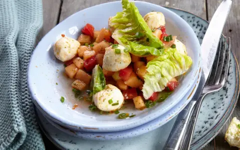 Erfrischender melonensalat mit mozzarella, Tomaten und knackigem Salat. Ein leichter Genuss für warme Tage.