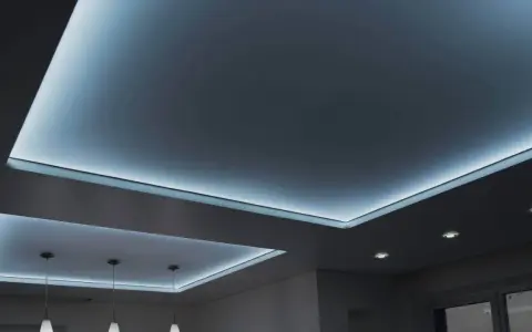 Nowoczesny sufit napinany z subtelnym, niebieskim podświetleniem tworzy relaksującą atmosferę.