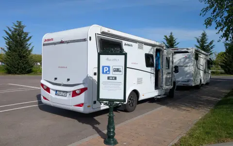 Wohnmobile parken am Europapark. Ein Schild weist auf die Parkgebühr von 20 € für Rulantica hin.