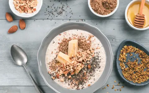 Avena con plátano, almendras picadas, chía y miel, rodeada de ingredientes.