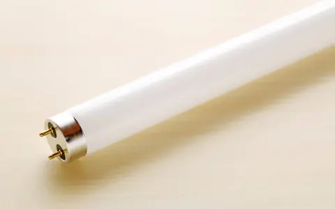 Tubo fluorescente con dos pines dorados, listo para cambiar por led y ahorrar energía.