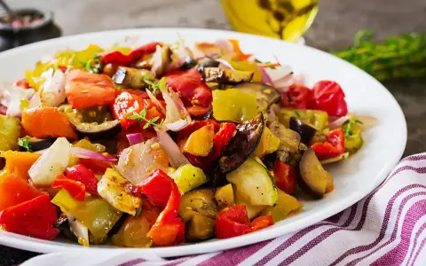 Un piatto colorato di verdure miste, pomodori, melanzane e peperoni, che evoca i sapori dei piatti tipici siracusani.