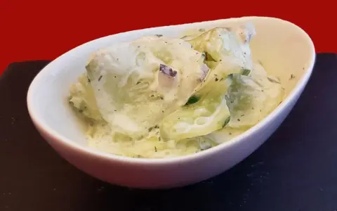 Salade fraîche de concombre à la crème, parsemée d'herbes fines. Un délice léger et savoureux.