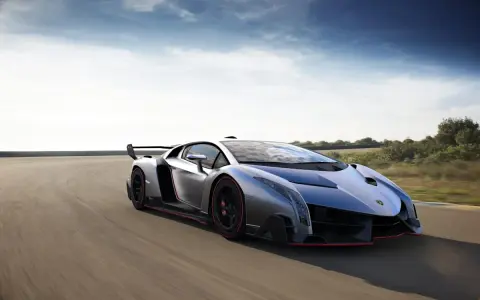Silberner Lamborghini Veneno Coupé rast auf einer Rennstrecke, die roten Akzente leuchten.