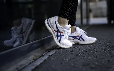 Vita Asics-skor med blå och röda detaljer, perfekt för löpning. Kolla in vår asics storleksguide för rätt passform.