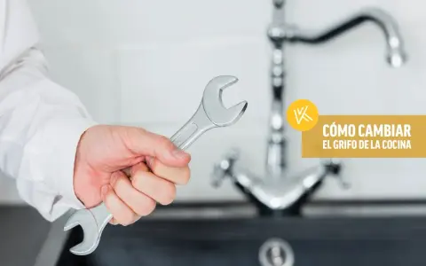 Mano con llave inglesa lista para instalar grifo cocina. Texto: "Cómo cambiar el grifo de la cocina".