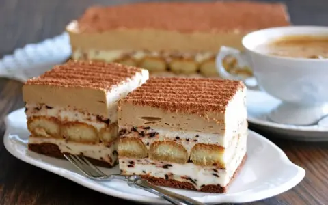 Pyszne ciasto cappuccino z biszkoptami i kremem, posypane kakao. Idealne na prosty przepis na ciasto cappuccino.