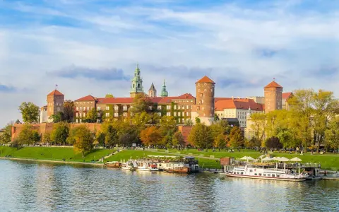 Wawel w jesiennej odsłonie, z łodziami na Wiśle. Poznaj ciekawostki o Krakowie, spacerując brzegiem rzeki.