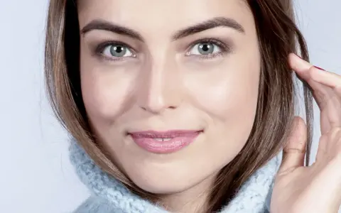 Visage de femme au regard intense, mettant en valeur ses sourcils parfaits. Elle porte un pull bleu ciel.