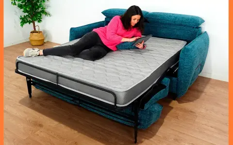 Mujer relajada en un sofá cama abierto, usando su tablet. Los sofabeds son perfectos para ahorrar espacio.