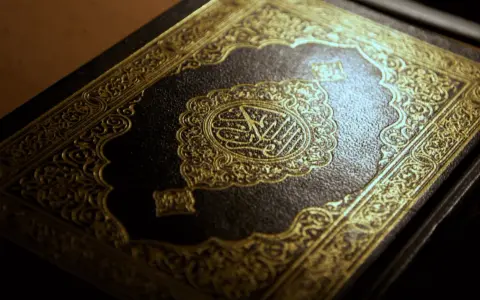 Ein prachtvoller Koran mit goldener Verzierung. Die Mitte ziert eine kunstvolle Kalligraphie, die an die Weisheit der **Surah Luqman** erinnert.