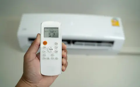 Mano che tiene un telecomando per condizionatore, impostato a 25°C. Il significato di "set temp condizionatore" è la temperatura desiderata.