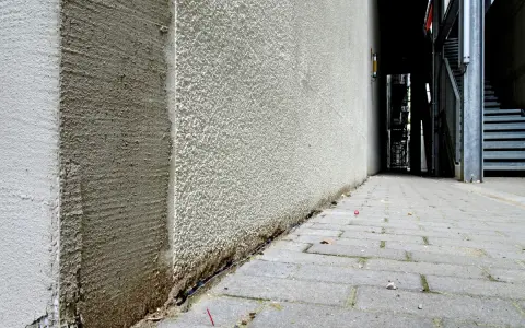 Die Ecke eines Gebäudes wird mit WDVS verputzt. Der Putz ist rau und hellgrau, mit sichtbaren Spuren der Verarbeitung.