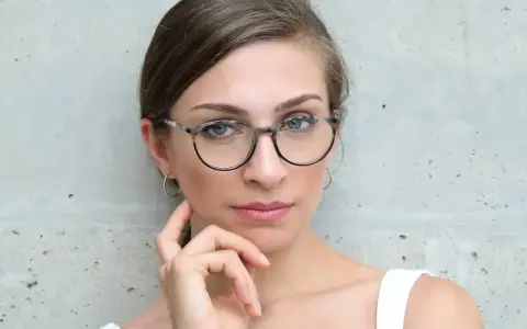 Eleganckie okulary dla szczupłej twarzy podkreślają spojrzenie kobiety.