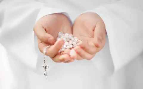 Dłonie trzymające różaniec, symbol modlitwy i intencje papieskie.