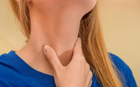 Kobieta dotyka swojej szyi, co może sugerować niepokojące nowotwór przełyku objawy, takie jak ból lub dyskomfort.